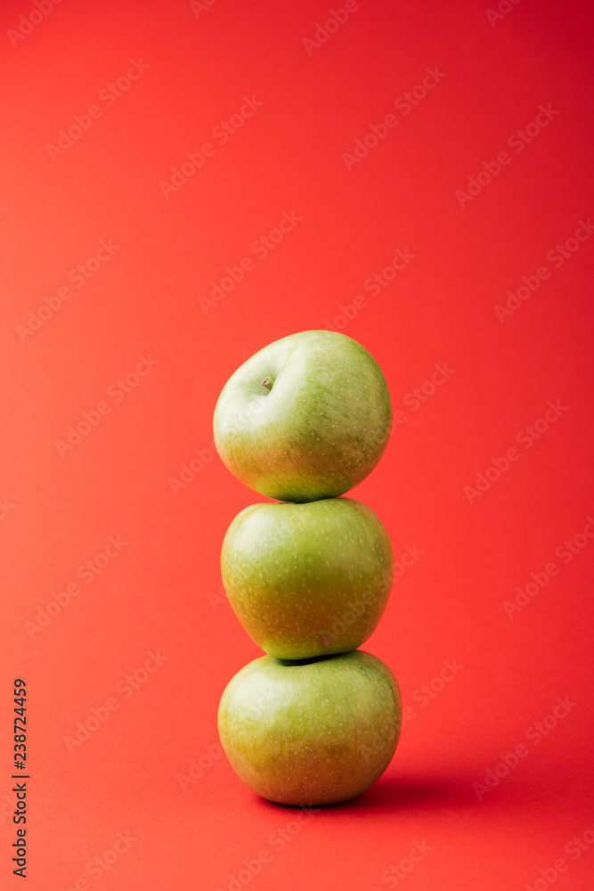 stack of three ripe green apples on red background stack of three ripe green apples on red background