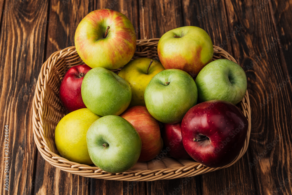 wicker basket with ripe multicolored apples on rustic wooden table wicker basket with ripe multicolored apples on rustic wooden table