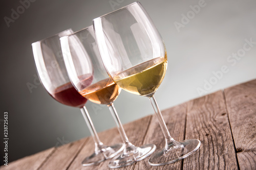 Glasses with white, rose and red wine on rustic old wooden table selective focus