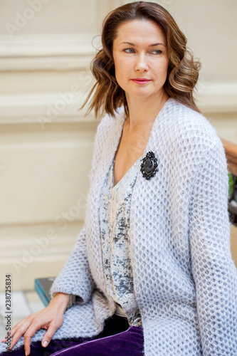 Obraz na płótnie beautiful middle-aged woman in a blue knitted jacket with a brooch