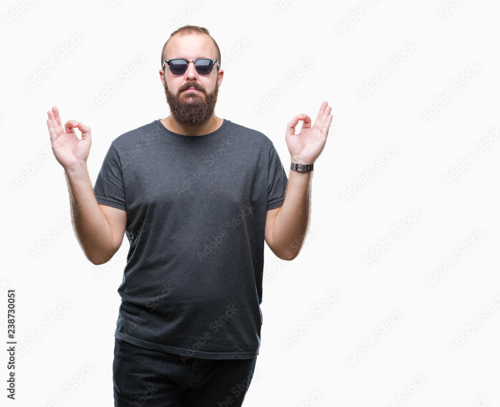 Young caucasian hipster man wearing sunglasses over isolated background relax and smiling with eyes closed doing meditation gesture with fingers. Yoga concept. Young caucasian hipster man wearing sunglasses over isolated background relax and smiling with eyes closed doing meditation gesture with fingers. Yoga concept.