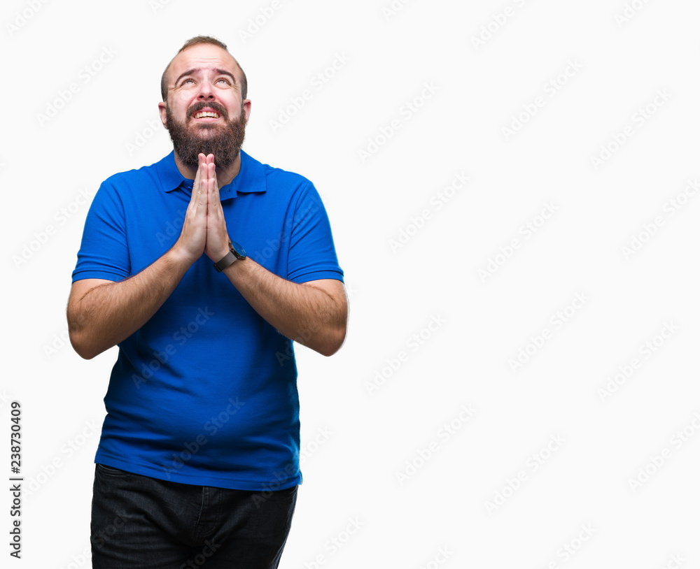 Young caucasian hipster man wearing blue shirt over isolated background begging and praying with hands together with hope expression on face very emotional and worried. Asking for forgiveness Young caucasian hipster man wearing blue shirt over isolated background begging and praying with hands together with hope expression on face very emotional and worried. Asking for forgiveness