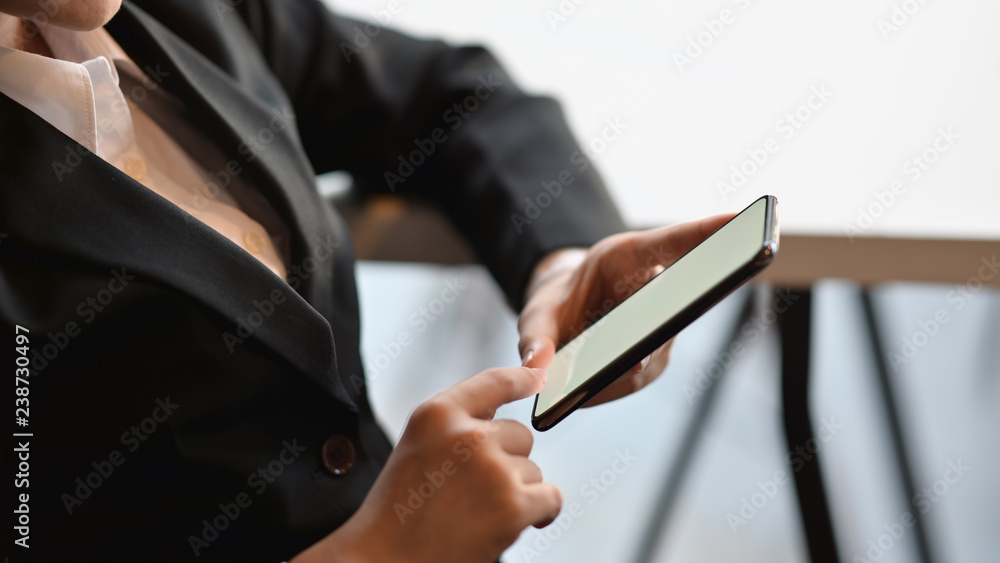 Cropped shot of a young businesswoman using on a smartphone in a modern office - obrazy, fototapety, plakaty 