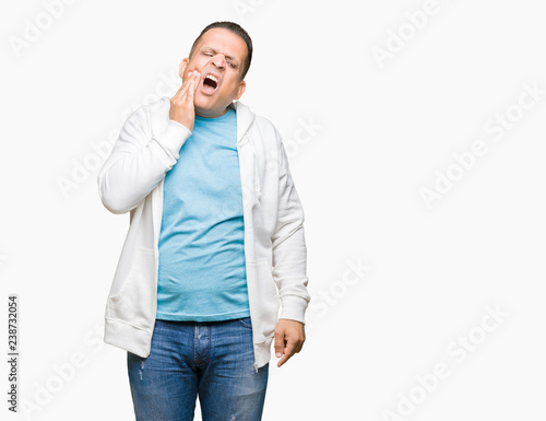Middle age arab man wearing sweatshirt over isolated background touching mouth with hand with painful expression because of toothache or dental illness on teeth. Dentist concept. © Krakenimages.com