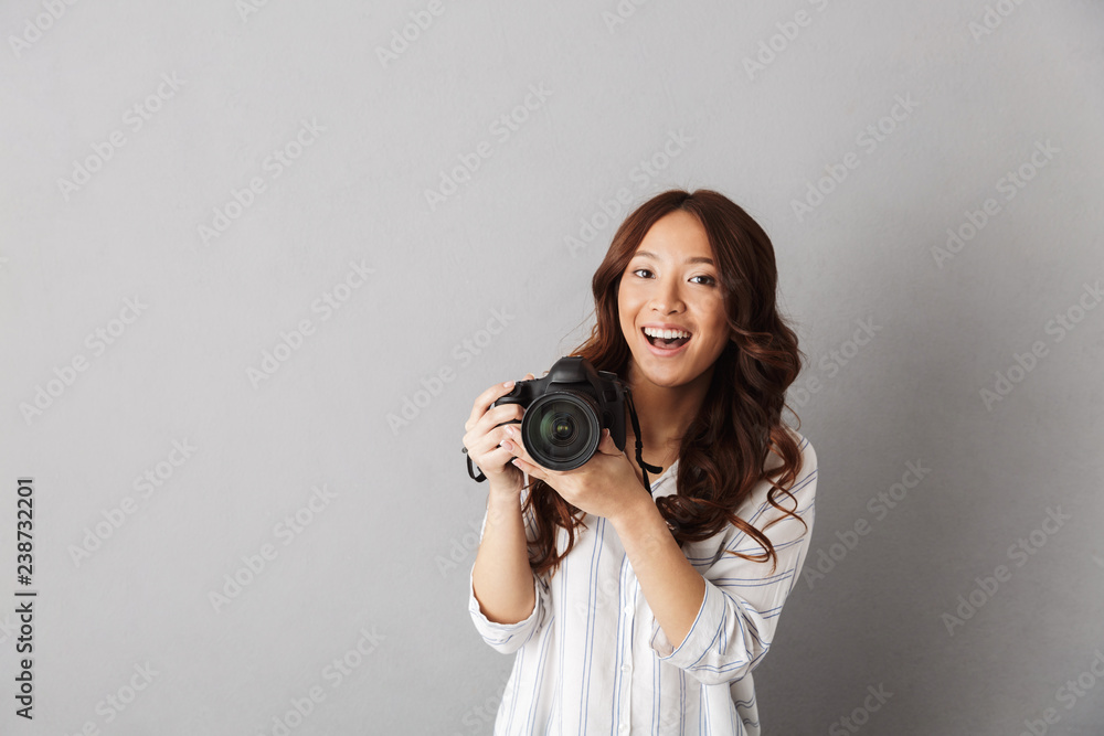 Cheerful asian woman standing isolated over gray Cheerful asian woman standing isolated over gray