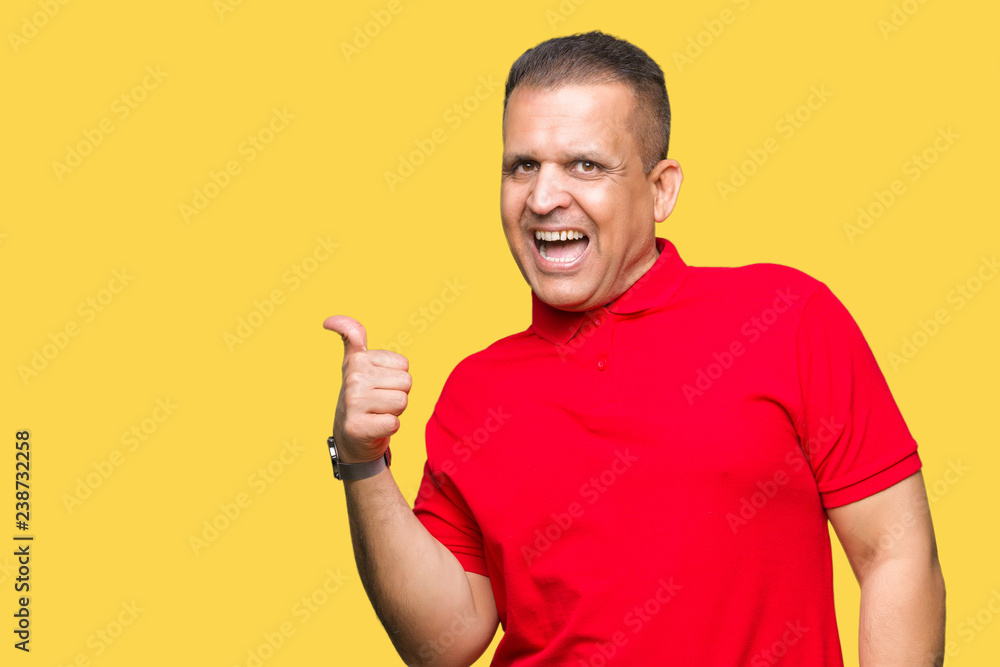 Middle age arab man over isolated background smiling with happy face looking and pointing to the side with thumb up. Middle age arab man over isolated background smiling with happy face looking and pointing to the side with thumb up.