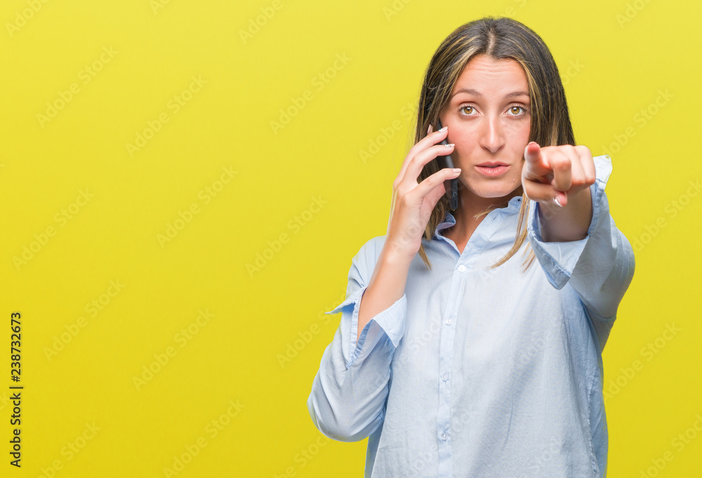 Young beautiful woman talking on smartphone over isolated background pointing with finger to the camera and to you, hand sign, positive and confident gesture from the front Young beautiful woman talking on smartphone over isolated background pointing with finger to the camera and to you, hand sign, positive and confident gesture from the front