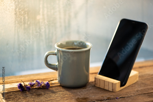 coffee mug and smart phone on wood table in cafe.