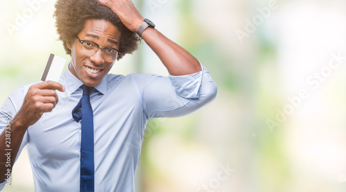 Afro american man holding credit card over isolated background stressed with hand on head, shocked with shame and surprise face, angry and frustrated. Fear and upset for mistake.
