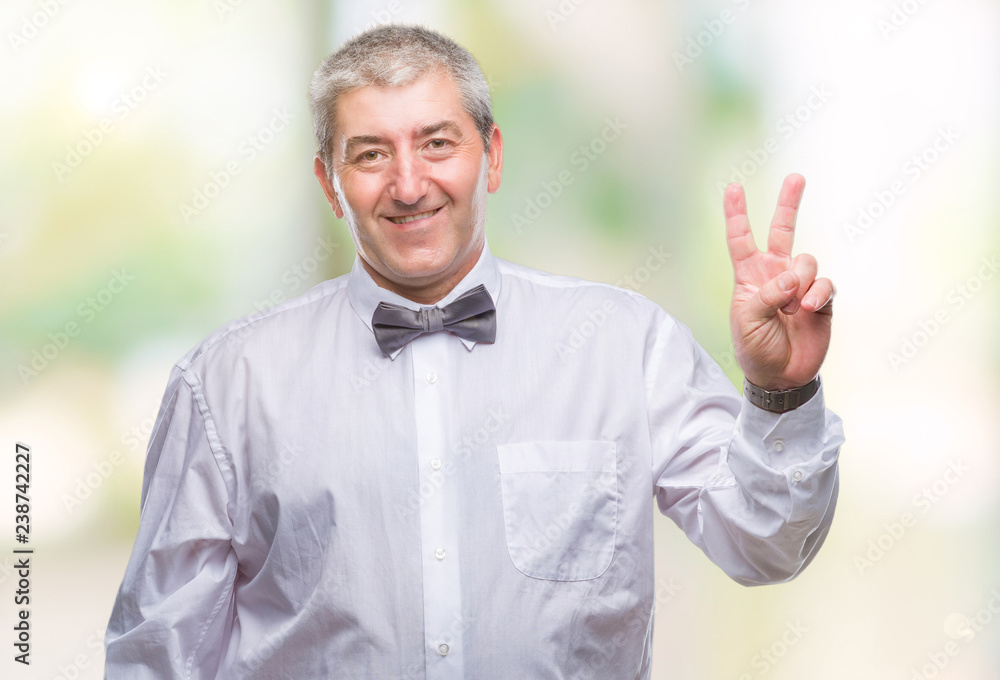 Handsome senior man wearing bow tie over isolated background smiling with happy face winking at the camera doing victory sign. Number two. Handsome senior man wearing bow tie over isolated background smiling with happy face winking at the camera doing victory sign. Number two.