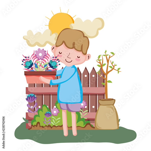 little boy lifting houseplant with fence in the garden