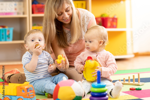 babysitter and children playing together in nursery or at home