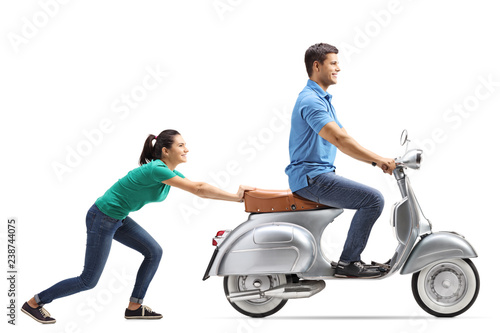 Full length shot of a young female pushing a guy on a vintage motorbike