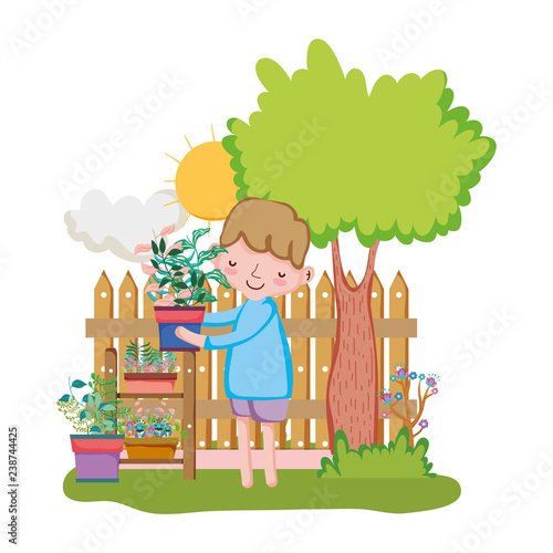 little boy lifting houseplant with fence and tree