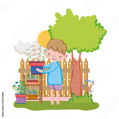 little boy lifting houseplant with fence and tree