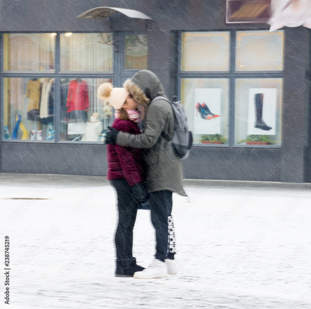 Couple in love kissing on the street of the city in snowy winter day. Defocused image