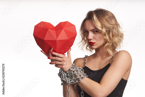 Woman holding red polygonal paper heart shape with tied by chain hands photo