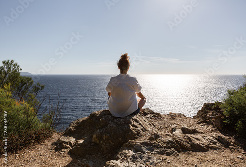 Femme assise en tailleur méditant face à la mer photo