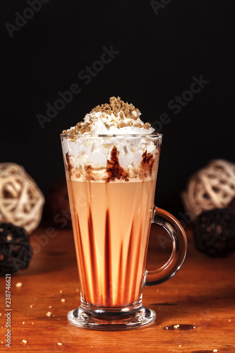 Beautifully designed latte macchiato coffee with whipped cream, in a high transparent glass, on a dark background