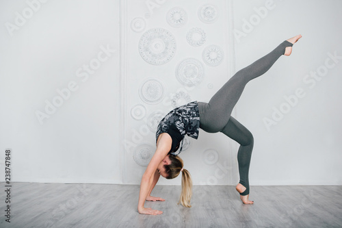 Young slender girl athlete performs fitness exercises and yoga