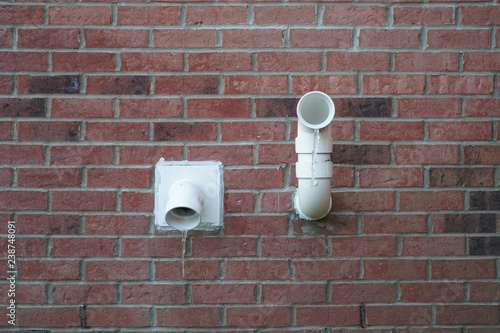 Two vents on a red brick house with hanging icicles