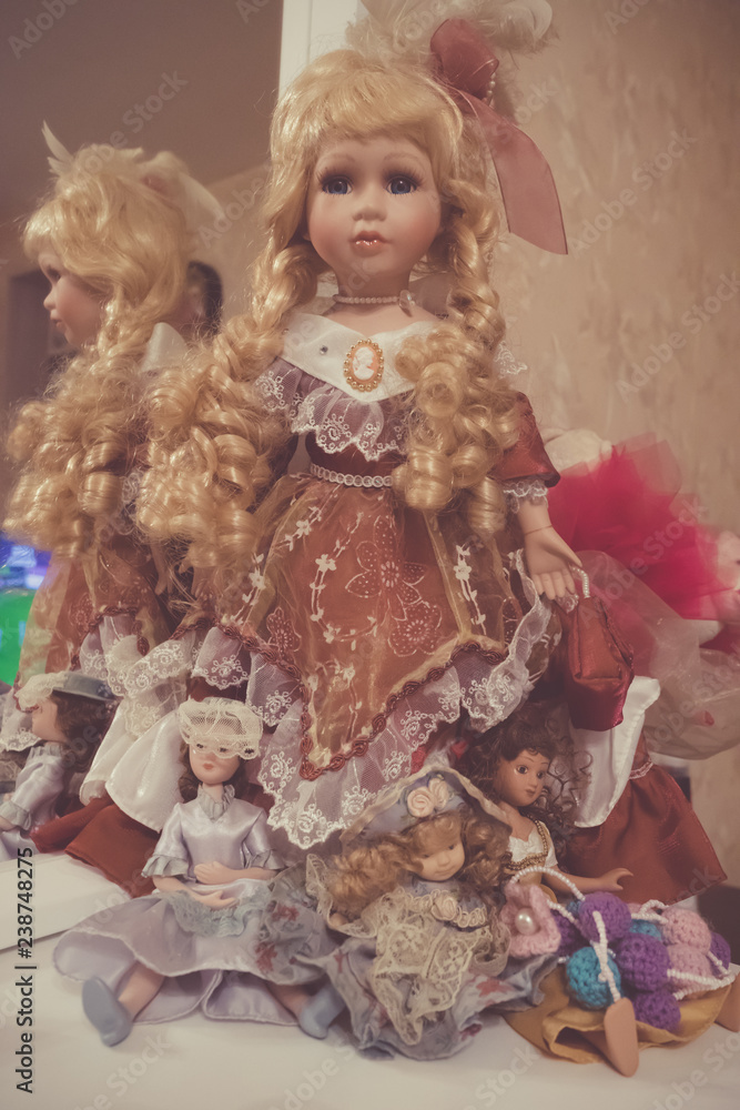 Old porcelain doll girl with blonde hair in vintage dress