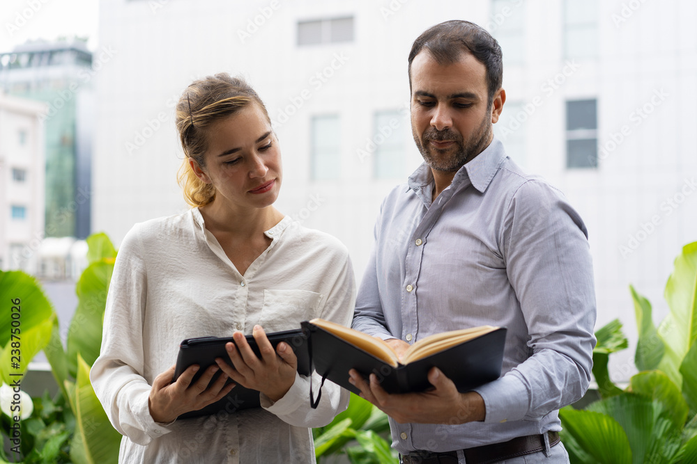 Serious boss and his assistant checking schedule. Two business employees looking at notes during break. Schedule concept Serious boss and his assistant checking schedule. Two business employees looking at notes during break. Schedule concept