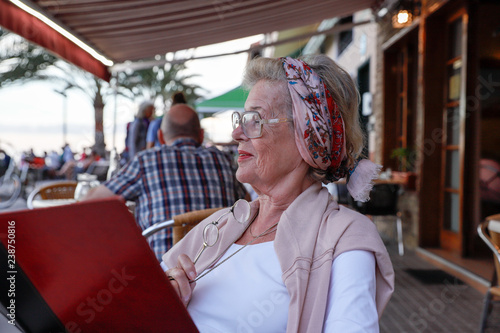 Attractive 78 year old woman during a summer restaurant visit. Authentic, natural, unplugged.