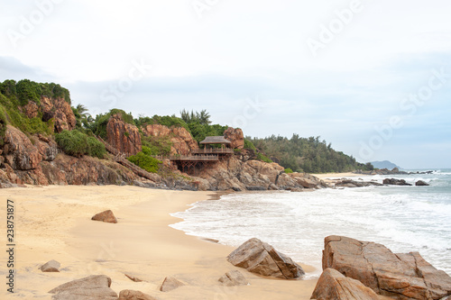 Red granite rock with tropical greenery on the beach