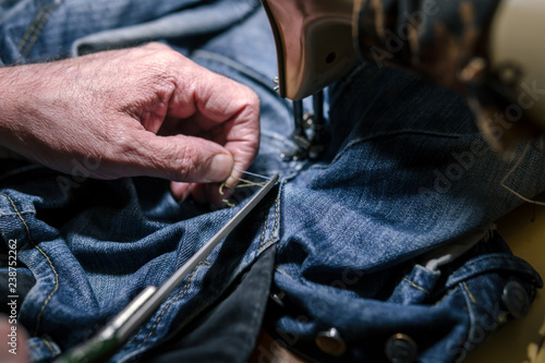 Closeup hands of Tailor man working on old sewing machine. jeans cloth fabric textile in shop, Tailoring, close up.