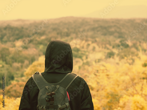 backpack and camping concept from backside of black hair man in warm hoodie sweatshirt with his bag solo travel, relax, happy and see to forest and mountain in morning after sunrise