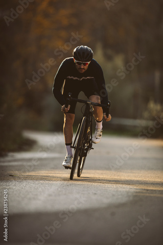 Professional road bicycle racer in action. Men cycling mountain road bike at sunset.