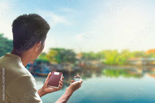 Man asian holding passport and compass standing beside sea or lake for activity lifestyle outdoors freedom or travel tourism and welcome happy new year 2019 image