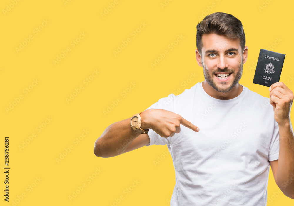 Young handsome man holding passport of united states over isolated background with surprise face pointing finger to himself Young handsome man holding passport of united states over isolated background with surprise face pointing finger to himself