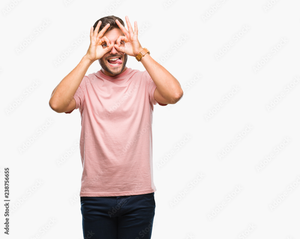 Young handsome man over isolated background doing ok gesture like binoculars sticking tongue out, eyes looking through fingers. Crazy expression. Young handsome man over isolated background doing ok gesture like binoculars sticking tongue out, eyes looking through fingers. Crazy expression.