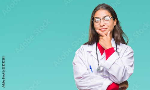 Young arab doctor woman over isolated background looking confident at the camera with smile with crossed arms and hand raised on chin. Thinking positive.