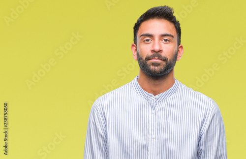 Adult hispanic man over isolated background with serious expression on face. Simple and natural looking at the camera. © Krakenimages.com