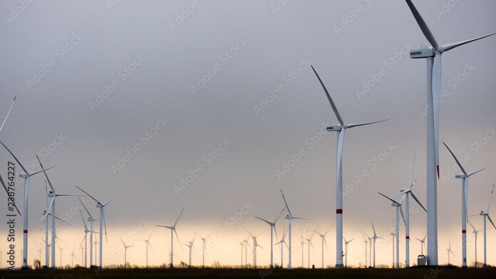 Obraz premium Wind Turbines, warm grey sky, copy space center left
