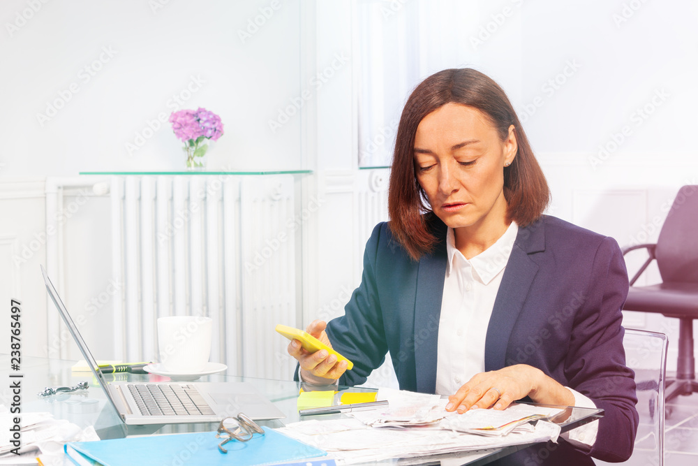 Businesswoman calculating bills using smart phone Businesswoman calculating bills using smart phone