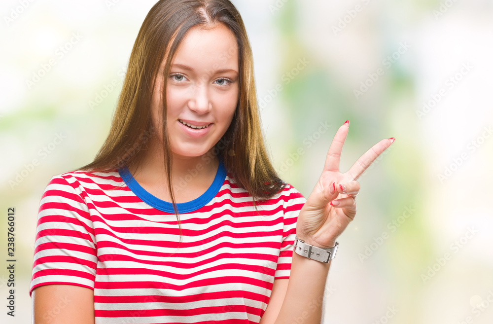 Young caucasian beautiful woman over isolated background smiling with happy face winking at the camera doing victory sign. Number two. Young caucasian beautiful woman over isolated background smiling with happy face winking at the camera doing victory sign. Number two.