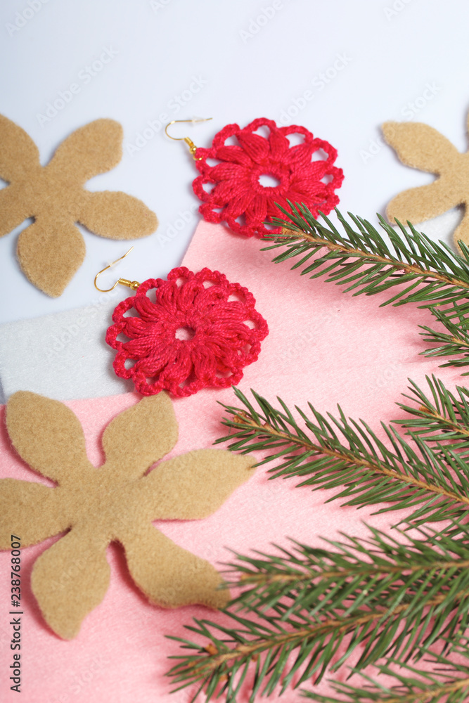 Knitted earrings on the background of felt fabric. Near spruce branch. Knitted earrings on the background of felt fabric. Near spruce branch.