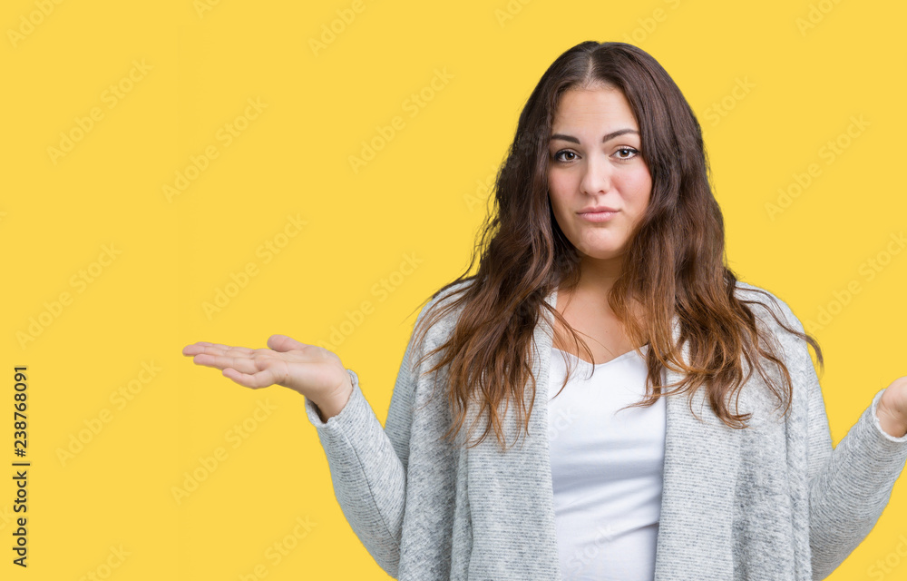 Beautiful plus size young woman wearing winter jacket over isolated background clueless and confused expression with arms and hands raised. Doubt concept. Beautiful plus size young woman wearing winter jacket over isolated background clueless and confused expression with arms and hands raised. Doubt concept.