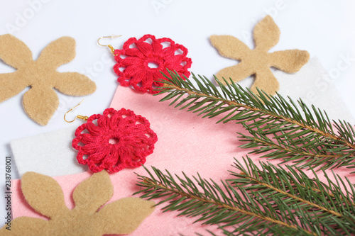 Knitted earrings on the background of felt fabric. Near spruce branch.