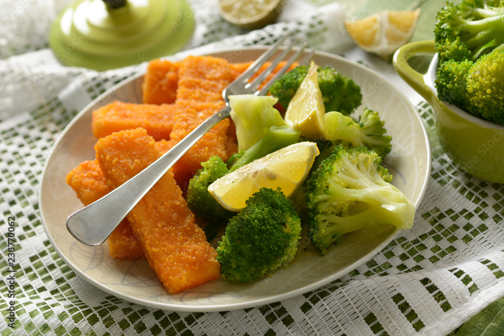 fish sticks with broccoli and lemon garnish