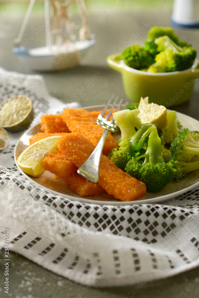 fish sticks with broccoli and lemon garnish