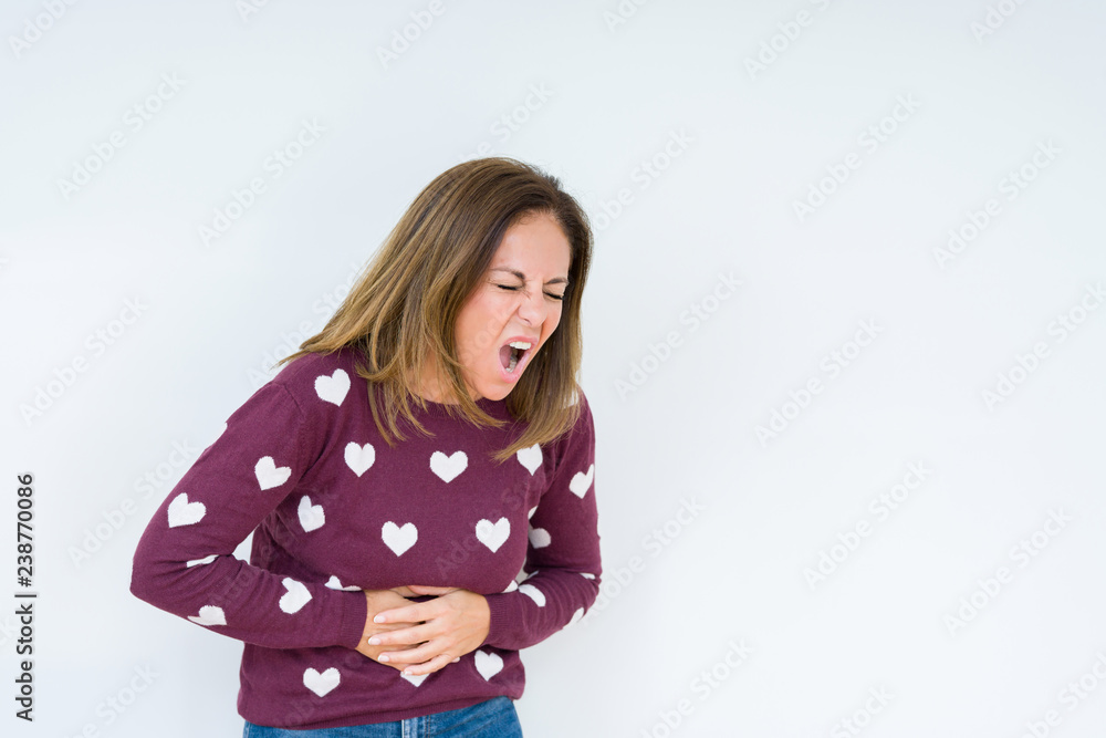 Beautiful middle age woman wearing heart sweater over isolated background with hand on stomach because nausea, painful disease feeling unwell. Ache concept. Beautiful middle age woman wearing heart sweater over isolated background with hand on stomach because nausea, painful disease feeling unwell. Ache concept.