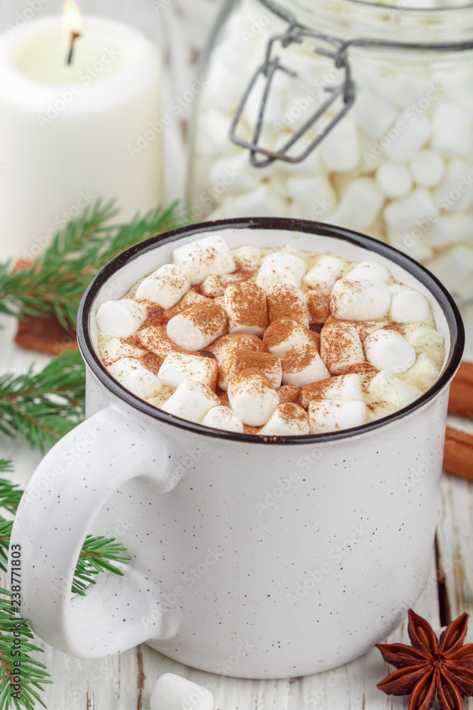 Hot cocoa (coffee or chocolate) with marshmallows and cinnamon in a white Cup. Candy, candles and fir branches on the table. Christmas. New year. Rustic style. Selective focus Hot cocoa (coffee or chocolate) with marshmallows and cinnamon in a white Cup. Candy, candles and fir branches on the table. Christmas. New year. Rustic style. Selective focus