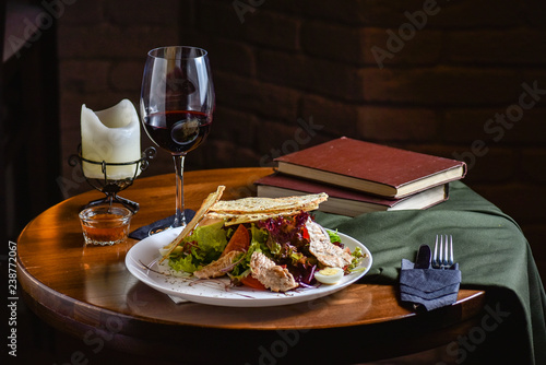 Serving at the restaurant a salad of fresh vegetables with meat and croutons. Dish with ingredients of meat and vegetables on the plate on a black wooden background, top view. Black background for