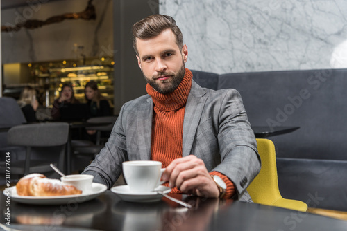 handsome man in formal wear looking at camera during lunch in restaurant