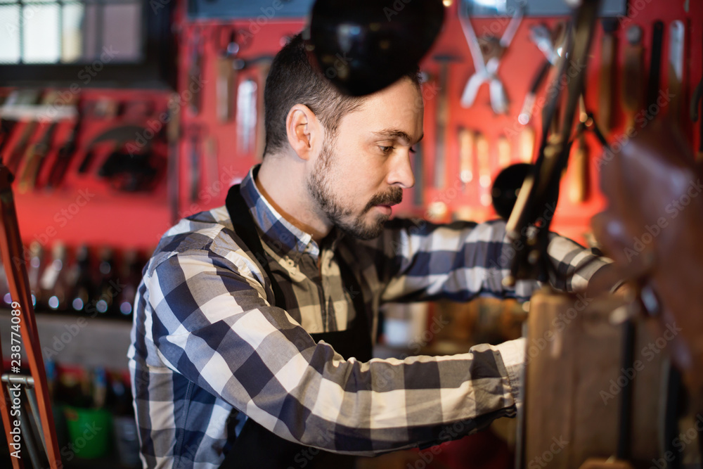 Fototapeta premium Male worker working on leather for belt in leather